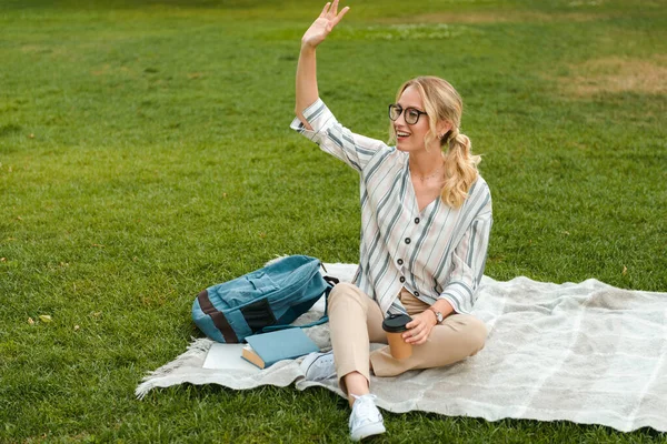 Krásná mladá blondýnka dívka relaxační na trávníku v parku — Stock fotografie