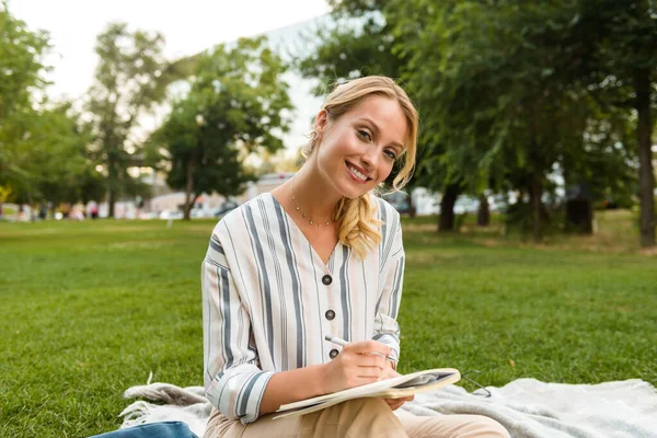 Schöne junge blonde Mädchen entspannt sich auf einer Liegewiese im Park — Stockfoto