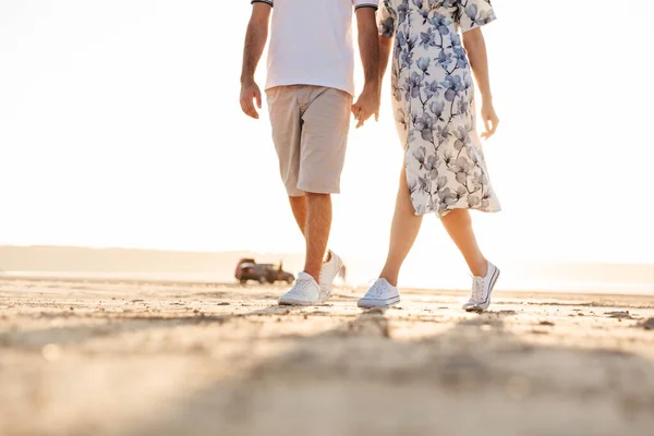 Foto recortada de hermosa pareja caucásica tomados de la mano mientras caminan en la playa soleada — Foto de Stock