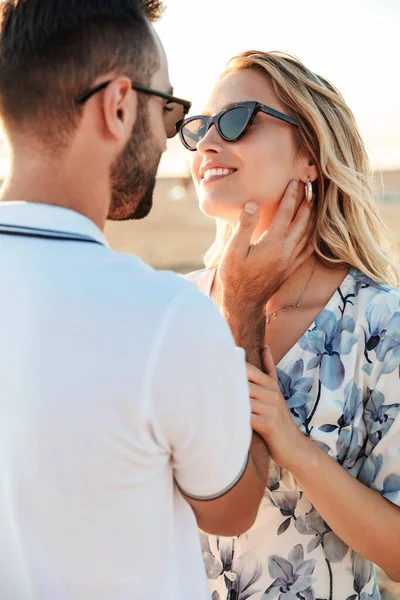 Фото романтичної молодої пари, посміхаючись і кидаючись один одному під час прогулянки на сонячному пляжі — стокове фото