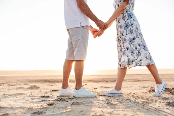 Foto recortada de pareja caucásica casual tomados de la mano mientras caminan en la playa soleada — Foto de Stock