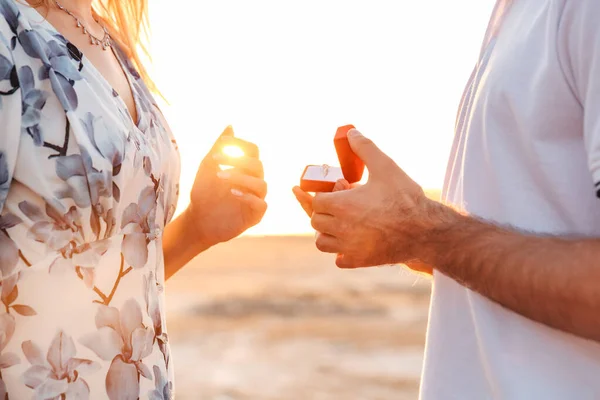 Abgeschnittenes Foto eines romantischen Mannes, der seiner Freundin beim Spazierengehen am sonnigen Strand einen Heiratsantrag macht — Stockfoto