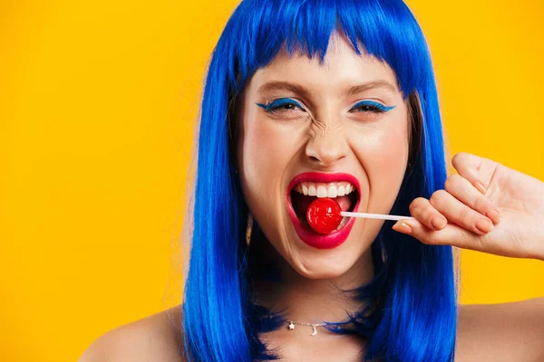 Ritratto di bella giovane donna che indossa parrucca blu mangiando lecca-lecca e guardando la macchina fotografica — Foto Stock