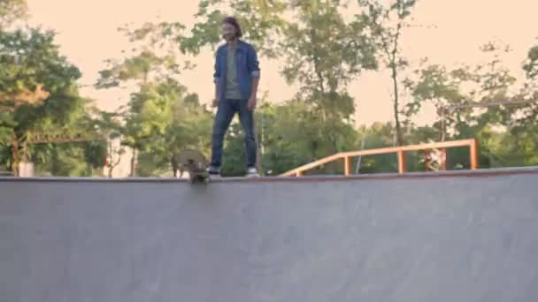 재킷을 젊은이가 경사로 근처에서 스케이트 공원에서 재미를 보면서 스케이트보드를 거기에 — 비디오
