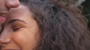 Dışarıda, karavanın yanında öpüşen ve kucaklaşan mutlu genç çiftin manzarası.