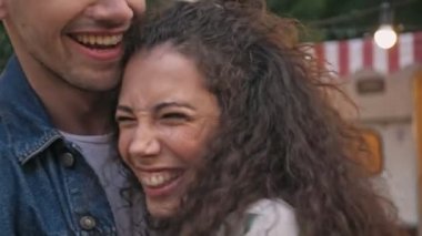 Parktaki karavanın yanında dans eden ve sarılan neşeli çiftin yakın görüntüsü.