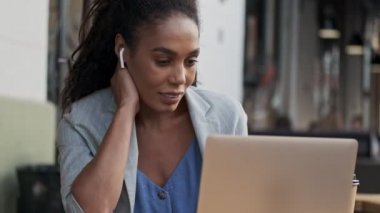 Kafede otururken dizüstü bilgisayarda çalışan konsantre olmuş, Afrikalı bir iş kadını.