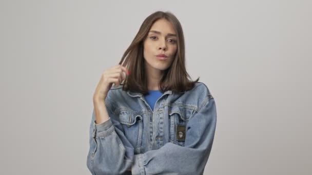 Kot Ceketli Düşünceli Genç Esmer Kadın Saçlarıyla Oynuyor Gri Arka — Stok video