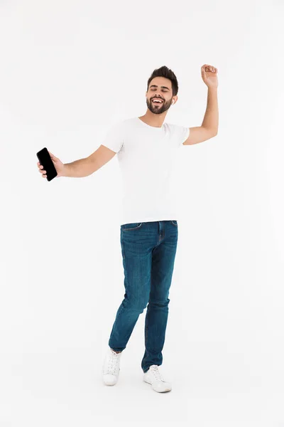 춤을 추면서 핸드폰 과 이어폰으로 음악을 듣고 있는 자유롭게 미소짓고 있는 남자의 모습 — 스톡 사진