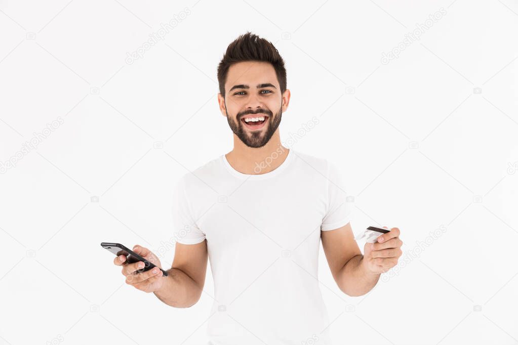 Image of laughing pleased man holding credit card and using cellphone