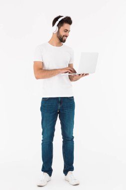 Laptop ve kulaklık kullanırken gülümseyen memnun bir adamın tam boy görüntüsü