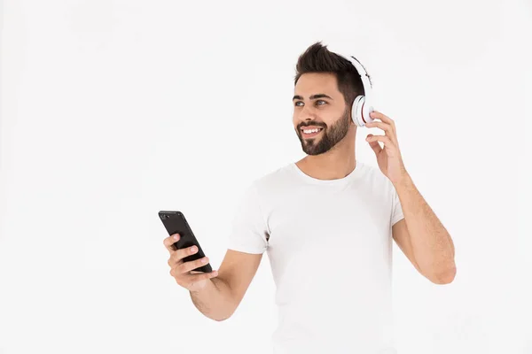 Afbeelding van ongeschoren tevreden man die muziek luistert op mobiele telefoon en hoofdtelefoon — Stockfoto