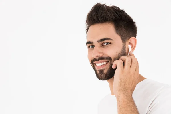 Imagen de primer plano del hombre guapo sin afeitar sonriendo y escuchando música con auricular — Foto de Stock