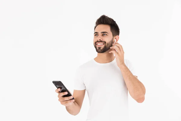 Imagen del hombre sonriente sin afeitar escuchando música con teléfono celular y auricular — Foto de Stock