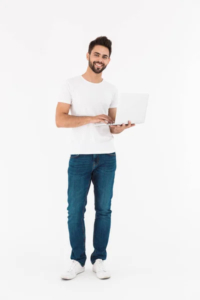 Imagem de comprimento total do homem jovem satisfeito sorrindo e usando laptop — Fotografia de Stock