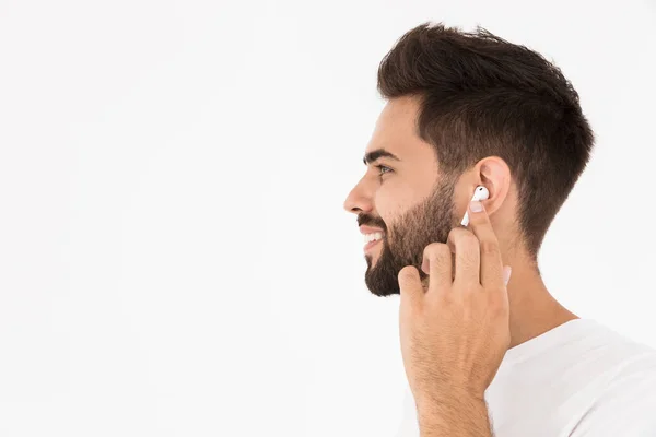 Imagen de primer plano del hombre sonriente sin afeitar escuchando música con auricular — Foto de Stock
