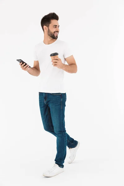 一个笑容满面的男人一边喝着咖啡一边用手机打字的全长形象 — 图库照片