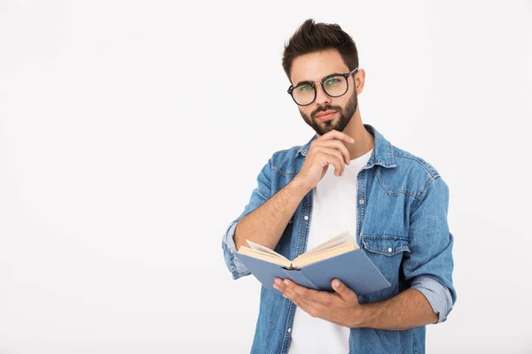 Bild av en seriös smart man med glasögon som håller i boken och tittar på kameran — Stockfoto