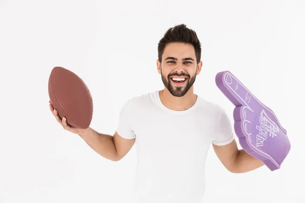 Imagen del sonriente hombre complacido sosteniendo la pelota de rugby y el guante de mano número uno con el dedo levantado — Foto de Stock