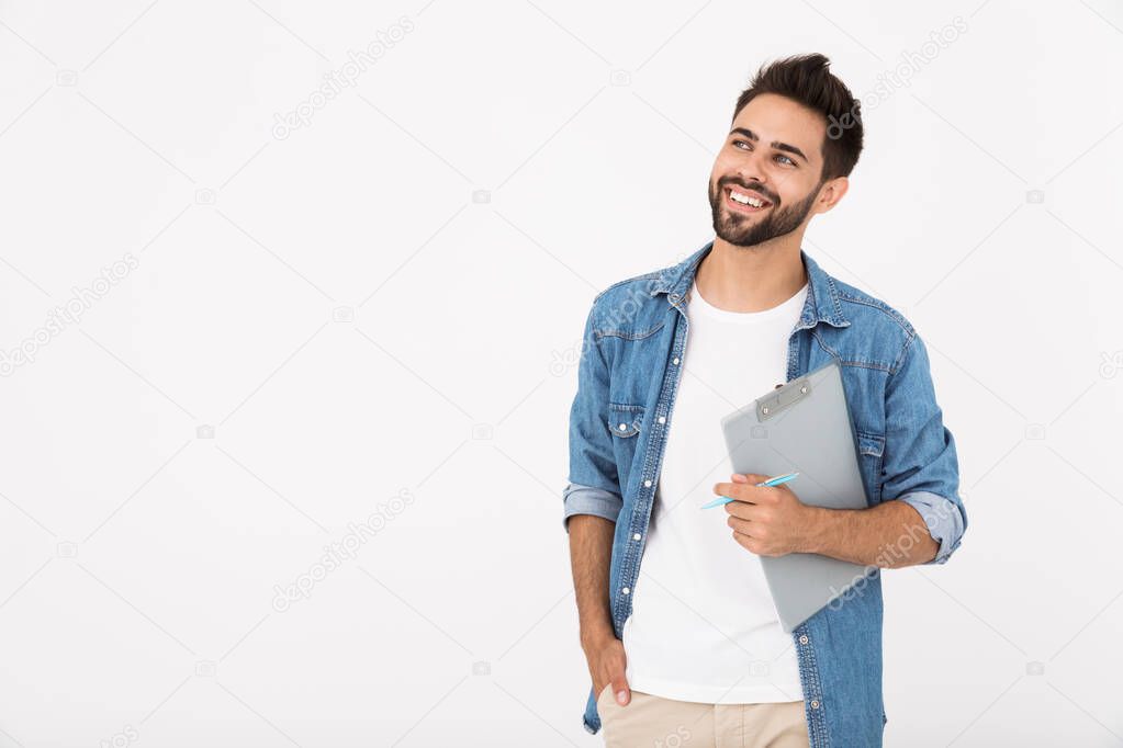 Image of cheerful young man holding clipboard and smiling looking upward at copyspace