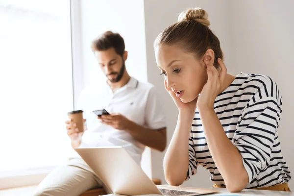 Koncentrerade unga kärleksfulla par vänner man och kvinna inomhus med bärbar dator dricka kaffe. — Stockfoto