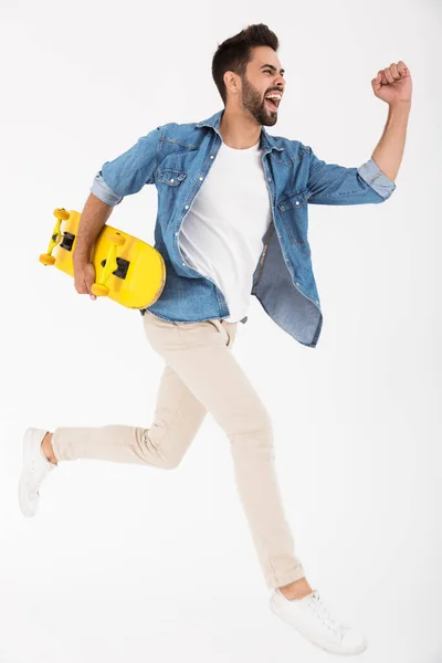 Imagem de comprimento total de jovem animado homem correndo e segurando skate — Fotografia de Stock