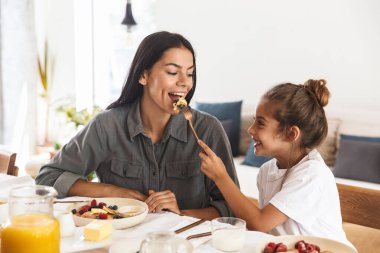 Lezzetli yemek yiyen muhteşem aile anne ve küçük kızın görüntüsü.