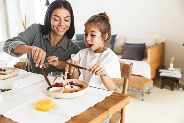 Зображення збудженої сім'ї матері та маленької дочки, що їсть перемикачі — стокове фото