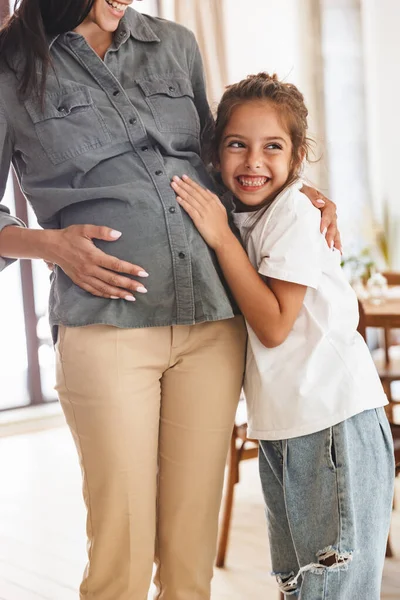 Imagen de la alegre niña emocionada sonriendo y abrazando a su preg —  Fotos de Stock