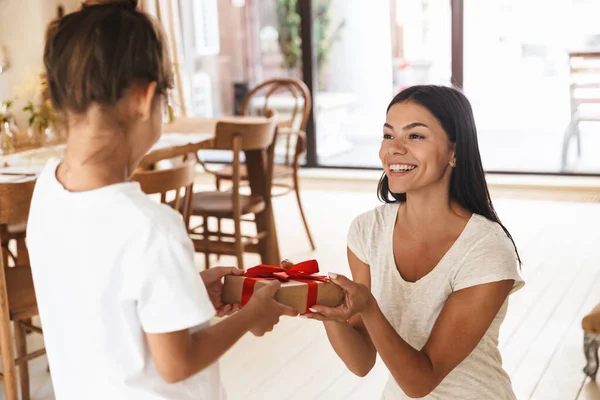 Beeld van gelukkig familie brunette moeder glimlachen en geven cadeau — Stockfoto