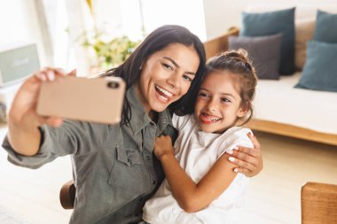 Neşeli bir aile resmi. Anne ve küçük kız selfie çekiyorlar. 