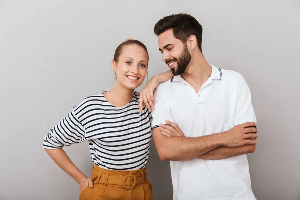 Усміхаючись щаслива молода любляча пара друзів чоловік і жінка позує в приміщенні ізольовано на сірому фоні . — стокове фото
