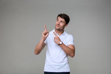 Yakışıklı esmer bir adamın gülümsemesi ve parmaklarını yukarı kaldırması.