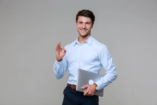 Bild eines selbstbewussten Geschäftsmannes, der Ok-Zeichen zeigt und Lapto hält — Stockfoto