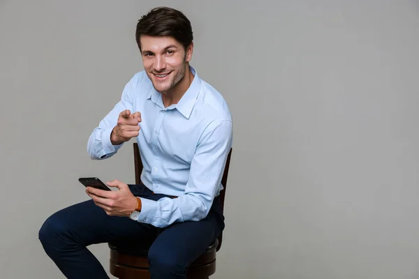 Portrait of businessman pointing finger at camera while holding — Stockfoto