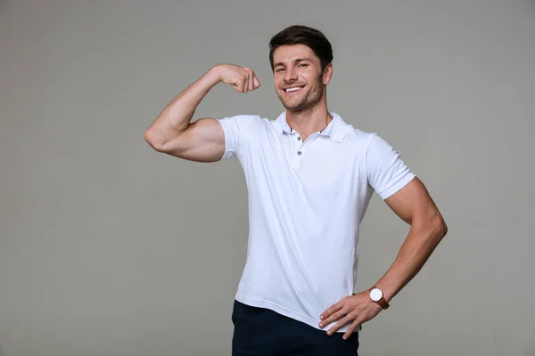 Image of attractive brunette man smiling and showing his bicep — ストック写真