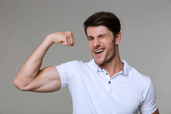 Bild av kaukasiska brunett man ler och visar sin bicep — Stockfoto