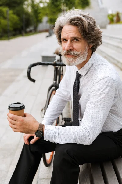 Photo of serious mature businessman drinking coffee takeaway — Stock Photo, Image