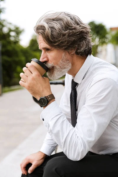 Фото зосередженого бородатого бізнесмена, який п'є винос кави — стокове фото