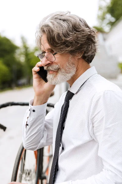 Photo of serous mature businessman talking on cellphone — Stock Photo, Image