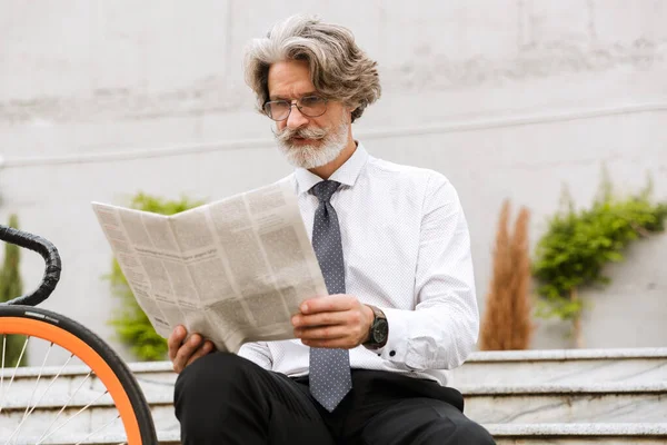 Foto de um empresário idoso sério lendo jornal — Fotografia de Stock