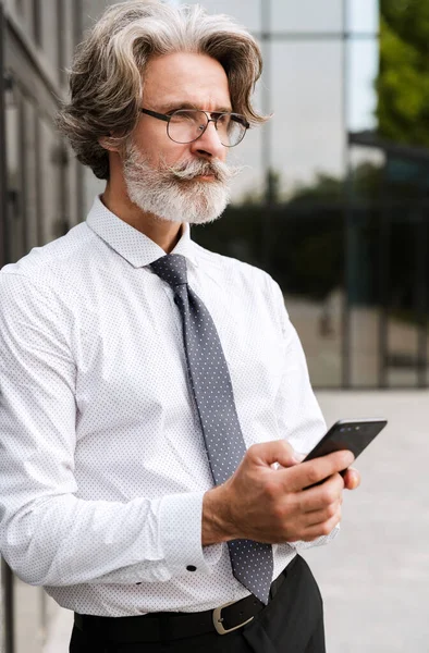 Photo of serous mature businessman typing on cellphone — Stock Photo, Image