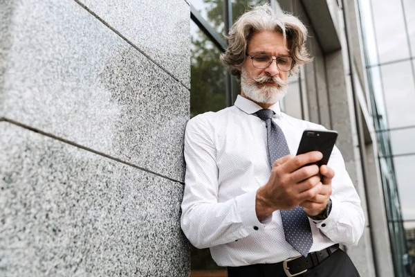 Фото концентрованого літнього бізнесмена, що друкує на мобільному телефоні — стокове фото