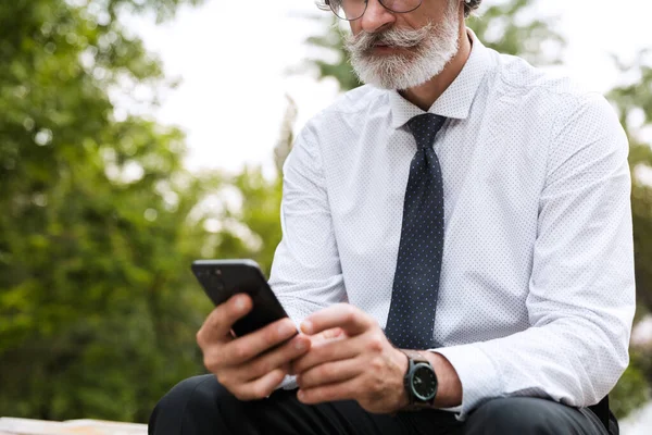 Przycięte zdjęcie starego myślącego biznesmena używającego telefonu komórkowego — Zdjęcie stockowe