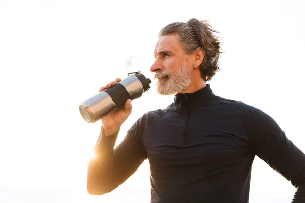 Image of sporty elderly man drinking water while working out — 스톡 사진