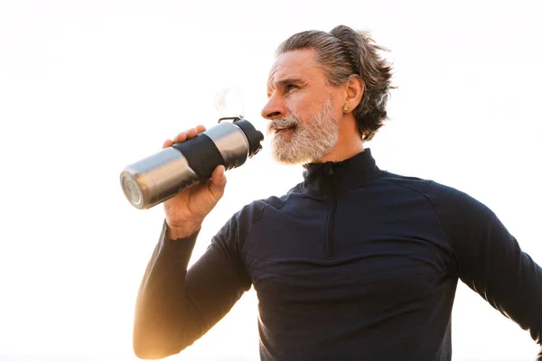 Immagine di uomo anziano che beve acqua dalla bottiglia mentre lavora fuori — Foto Stock