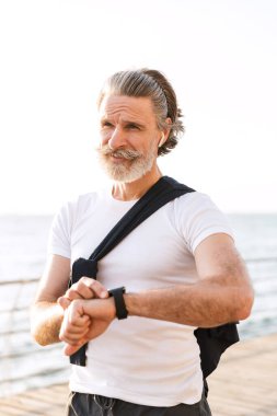 Akıllı kulaklık ve kulaklık kullanan neşeli yaşlı bir adam görüntüsü