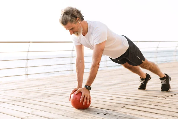 Immagine di vecchio sportivo che fa esercizio con la palla medica — Foto Stock