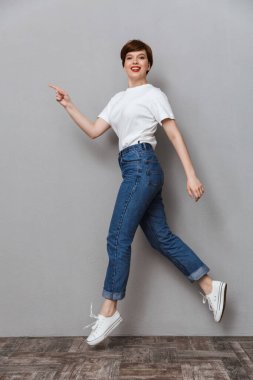 Full length image of pretty brunette woman walking and pointing 