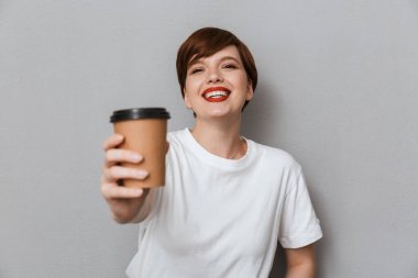 Image of young brunette woman smiling and holding takeaway coffe